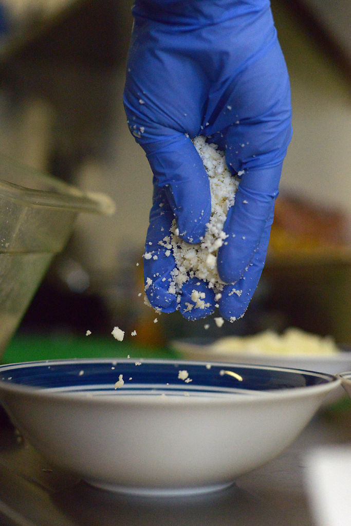 Colin Enslin grounds up queso fresco for taco toppings